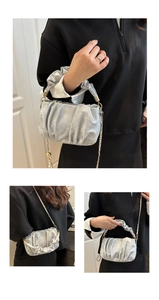 Macro detail of the metallic silver pleated handbag with gold chain strap and branding
