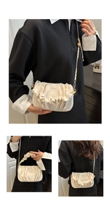 Detail of cream pleated cloud bag with gold chain strap and elegant brand logo lettering