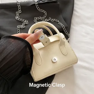 Detail of minimalist cream crossbody bag featuring a secure golden magnetic clasp and chain