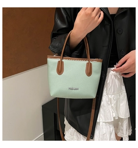 Vue macro détaillée du cuir grainé vert menthe et du logo argenté sur le petit sac