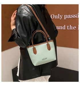 Détail de la texture en cuir vert menthe et du logo métallique FASHION sur le sac à main