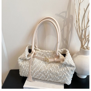 Detailed texture of ivory tweed tote bag with smooth leather straps and gold buckles