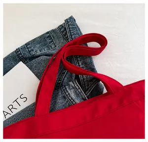 Close-up of the wide fabric handles and fine stitching on a bright red nylon tote bag
