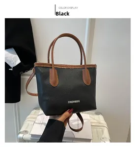 Détail du sac cabas en cuir grainé noir avec anses marrons et inscription mode