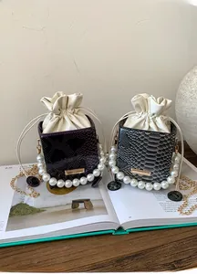 Detail of drawstring bucket bags with textured python skin and elegant pearl handles