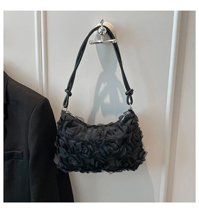 Détail des fleurs 3D sur un sac à bandoulière noir en tulle avec bandoulière à nœuds