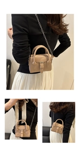 Detalle del bolso cuadrado beige con correa de cadena plateada y asa superior fija