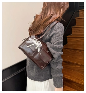 Deep brown glossy PU shoulder bag featuring lace bow and pearl heart charm on model
