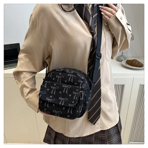 Détail d'un sac bandoulière en velours côtelé noir avec motifs nœuds gris et cœurs