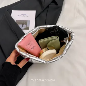 Detail view showing large capacity of the silver puffy clutch with daily essentials
