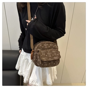 Détail du sac bandoulière en velours côtelé marron avec nœud et poche à rabat