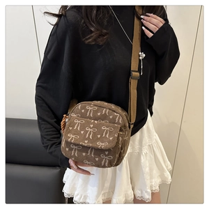 Sac à bandoulière en velours côtelé marron à nœuds, porté par un mannequin en intérieur
