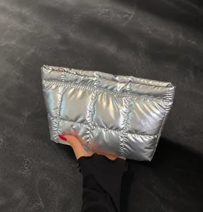 Close-up of a silver metallic quilted handbag featuring a golden zipper and tech-chic design