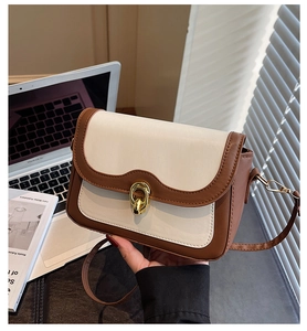 Detailed view of the wavy flap and golden twist lock on the two-tone crossbody bag