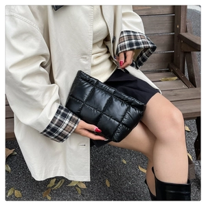 Close-up of black quilted puffer clutch bag with glossy waterproof nylon and square padding