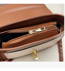 Detailed interior of a brown and cream crossbody bag with a zipper compartment and gold lock