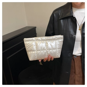 Close-up of quilted white pearlescent handbag featuring a puffy texture and metallic finish