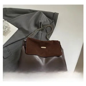 Detail of dark brown leather patchwork shoulder bag with gold chain and metal emblem