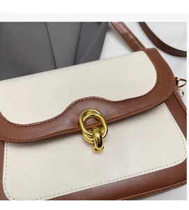 Detail of white and brown leather patchwork crossbody bag with golden metal ring clasp