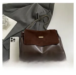 Detail of dark brown chain shoulder bag featuring leather and suede textures with a logo