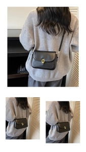 Detailed close-up of matte black leather crossbody bag with golden horseshoe-shaped metal buckle