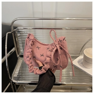 Pink corduroy shoulder bag with black bow patterns and ruffled handle design