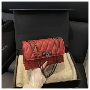 Dettaglio borsa trapuntata rossa con catena e fibbia geometrica in confezione regalo