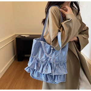 Detail of blue and white gingham tote bag featuring triple-layered ruffled edges and drawstring