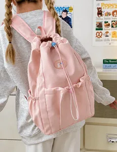 Pink drawstring nylon backpack for college students shown on model in school setting