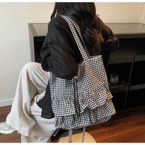 Detail of checkered tote bag with double ruffle pleated trim shown on model shoulder