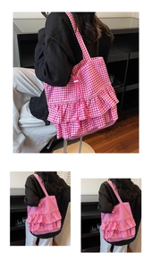 Detail of pink plaid tote bag with ruffled edges and drawstring closure on shoulder strap