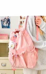 Pink waterproof nylon backpack with bear keychain shown on model for size reference