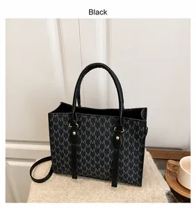 Dettaglio borsa shopper nera con motivo a M, manico e tracolla regolabile inclusi