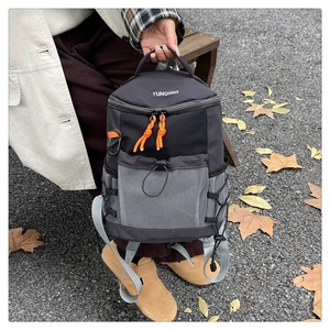 Detail of multi-functional black backpack with gray mesh pockets and orange zipper pulls