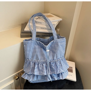 Detail of blue and white checkered tote bag featuring ruffle edges and drawstring closure