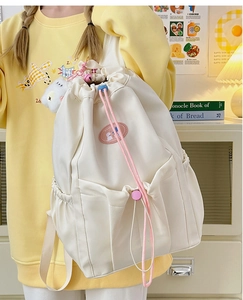 Detailed close-up of white waterproof nylon drawstring backpack with pink cartoon patch