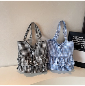 Detail of plaid tote bags with double ruffles and drawstrings in black and blue