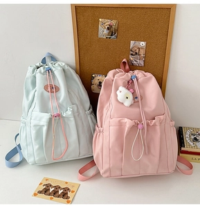 Detail view of pink and light blue college backpacks with drawstring and bear charm