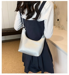 Vista de modelo de un bolso de hombro plateado con textura de cuero metalizado