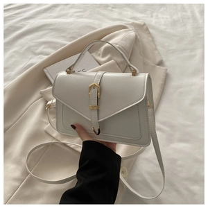 Detail van witte lederen crossbodytas met gouden gesp en verstelbare riem