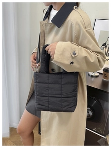 Detail of black quilted shoulder bag with puffy texture on model in urban cafe setting