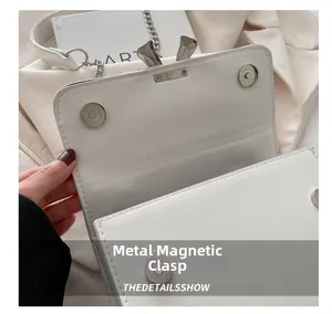 Detail of silver magnetic snap closure on premium white leather crossbody bag