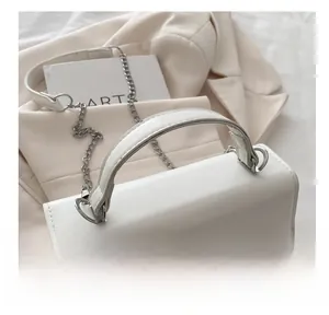 Detail of white PU leather handbag featuring silver bow buckle and elegant handle