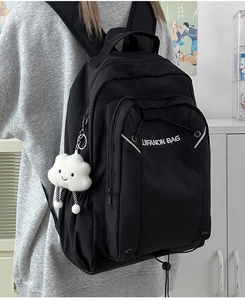 Side view of a black minimalist large capacity backpack with a white cloud pendant