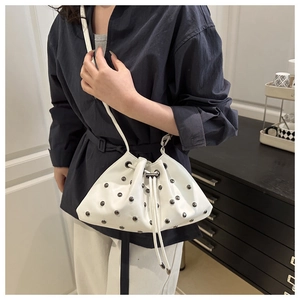 Detail of white drawstring bucket bag with silver metal studs on soft PU leather
