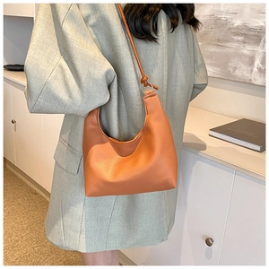 Détail du sac à bandoulière orange en forme de croissant avec texture grainée et boucle