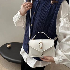 Sac bandoulière blanc minimaliste avec boucle dorée et poignée porté par mannequin
