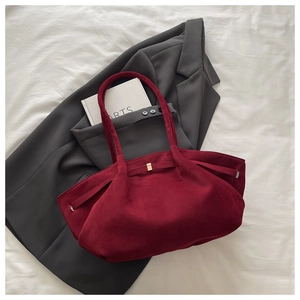Detailed close-up of burgundy suede tote bag with gold metal hardware on grey blazer
