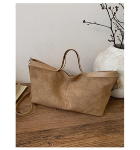 Detail of vintage caramel suede tote bag with wide handles on a rustic wooden table