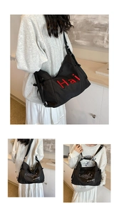 Macro shot of red Hai embroidery and white artistic script on black nylon tote bag